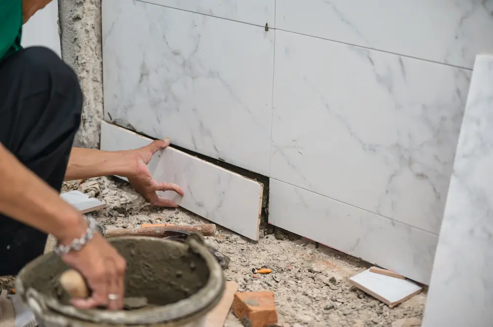 Persona instalando cerámica en la ducha